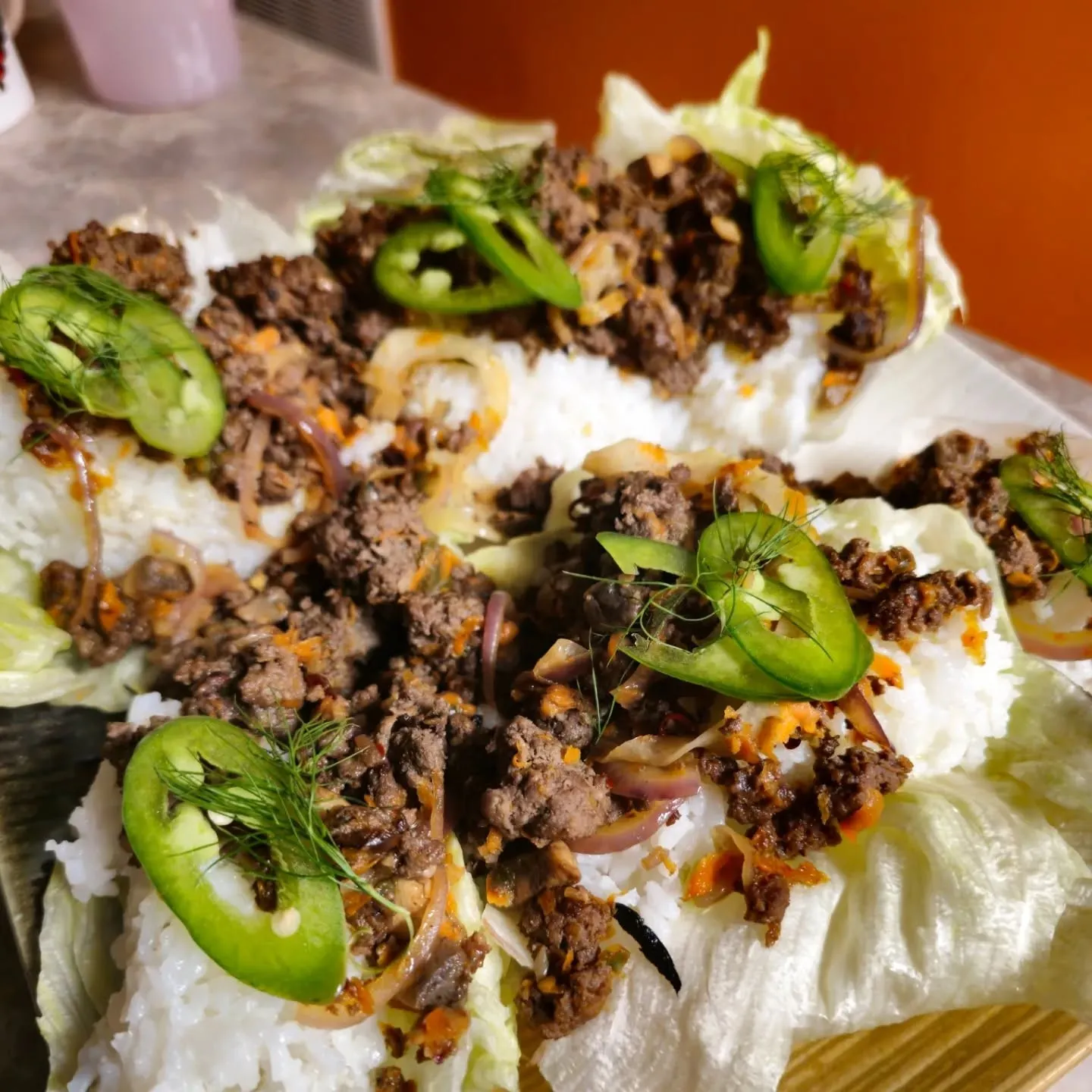 Lettuce cups filled with browned crumbles, sliced jalapeños and a white sauce.