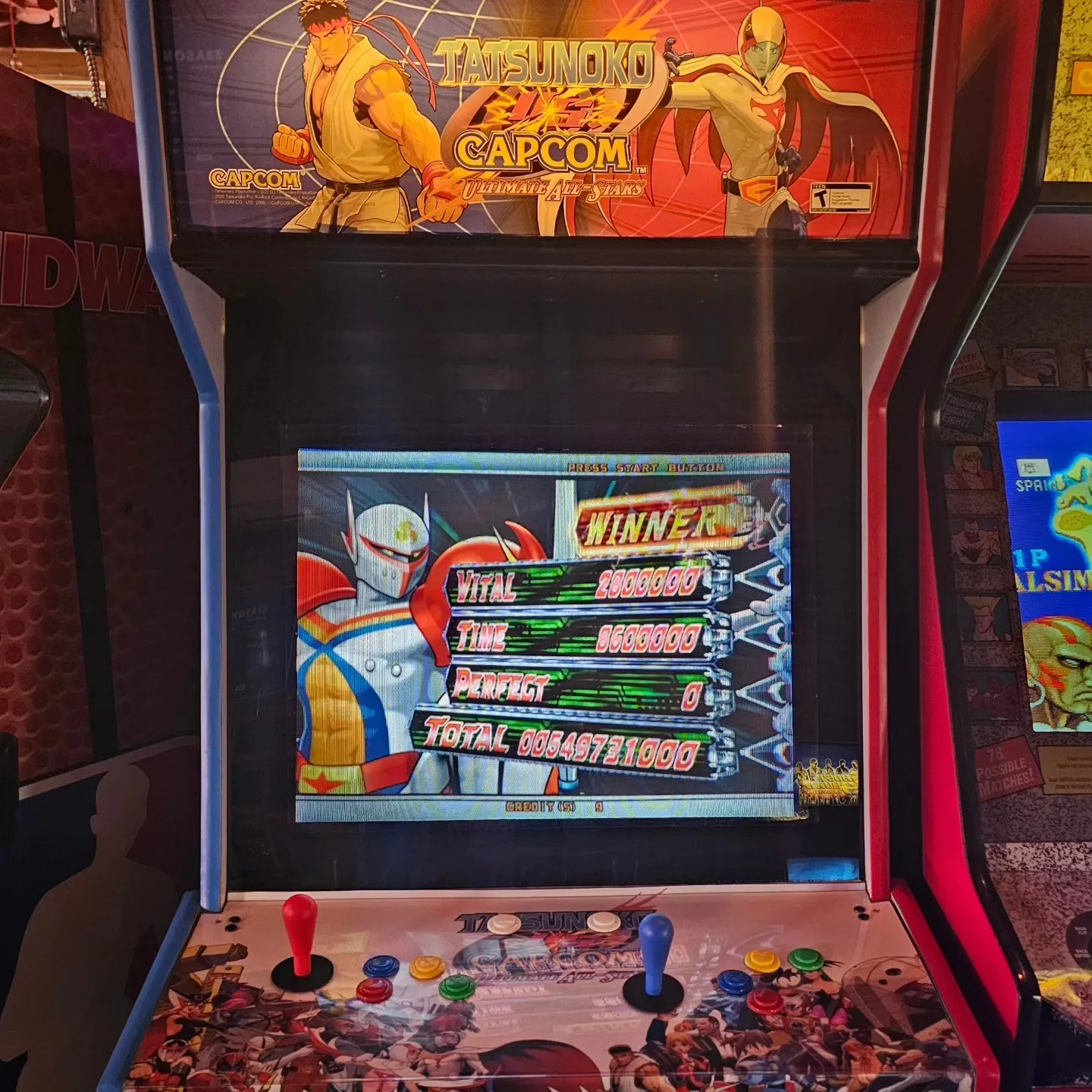 An arcade fighting game shows a winner screen beneath a Capcom marquee.