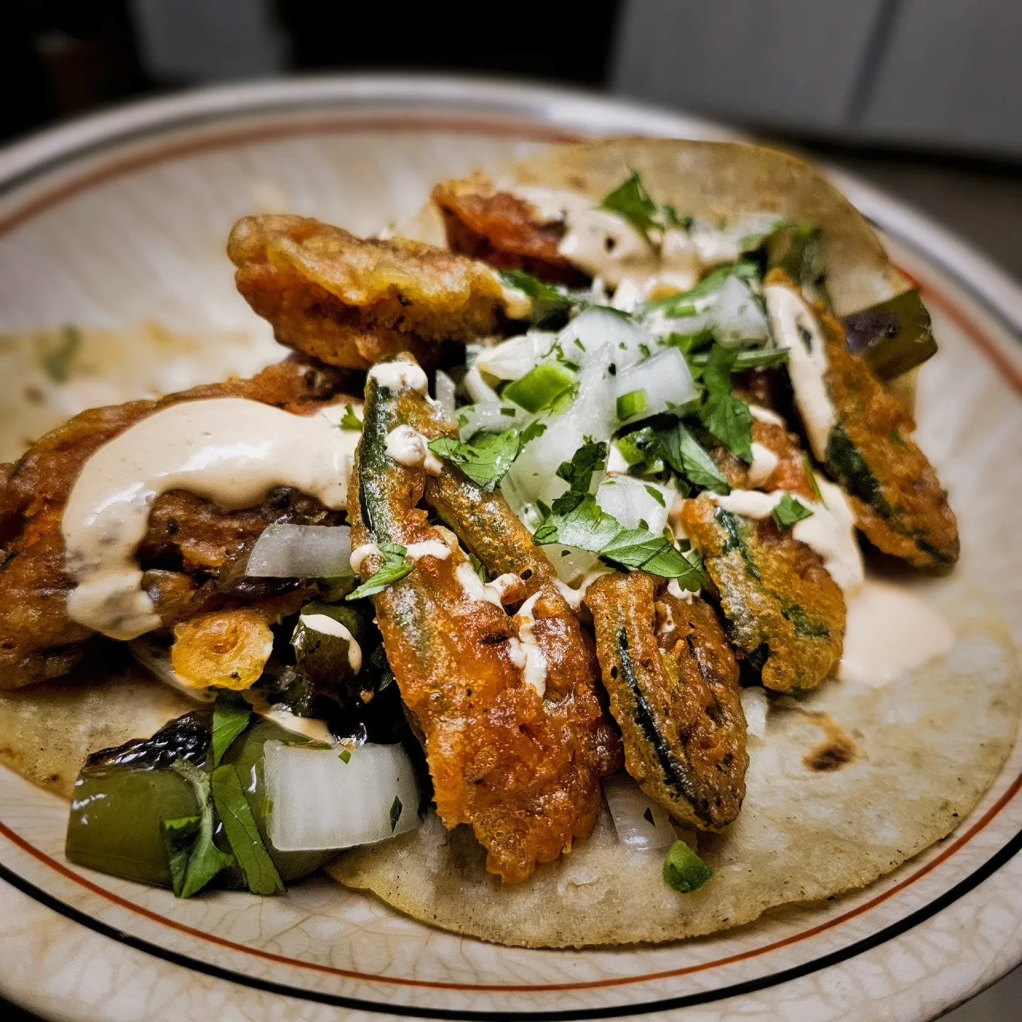 Flatbreads topped with browned strips, chopped onion, greens and a drizzle of white sauce.