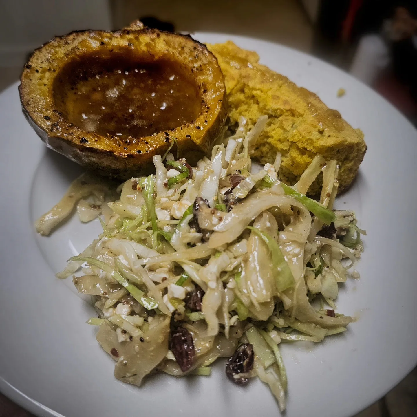 Roasted squash filled with sauce, served beside bread and a creamy shredded salad.